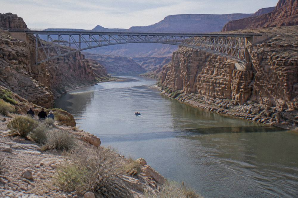 Calm river stretch between sheer rock cliffs with a small raft in the distance