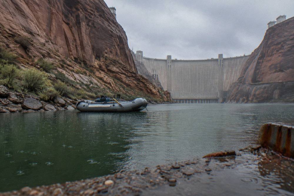 A raft resting on calm green water beneath steep rock canyon walls