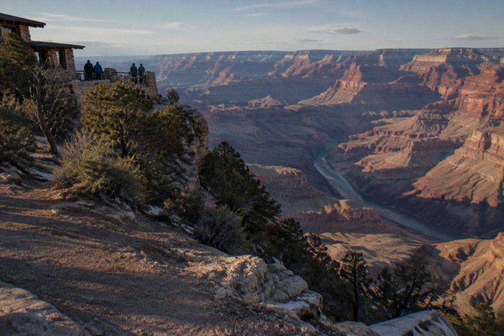 Wide view of layered red canyon walls above a stretch of quiet river