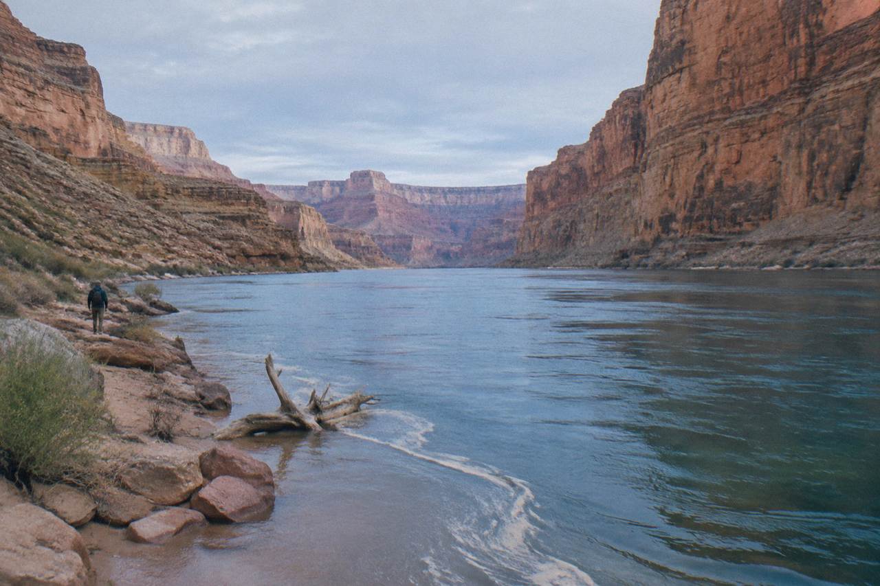 Calm blue river water winding between tall canyon walls under a wide sky