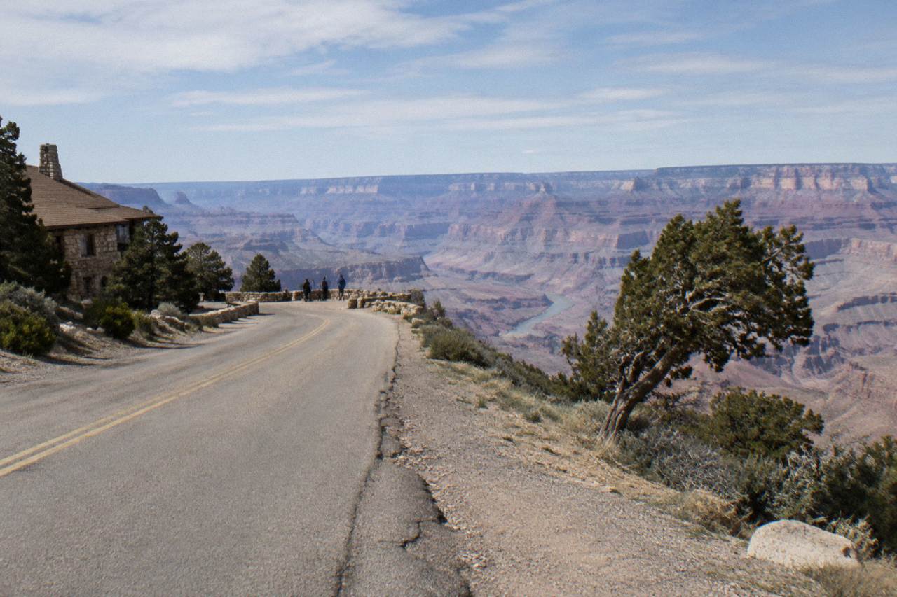 A desert highway cutting toward distant canyon mesas under a wide sky