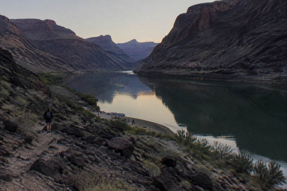 Still river water mirroring tall dark canyon walls in low desert light