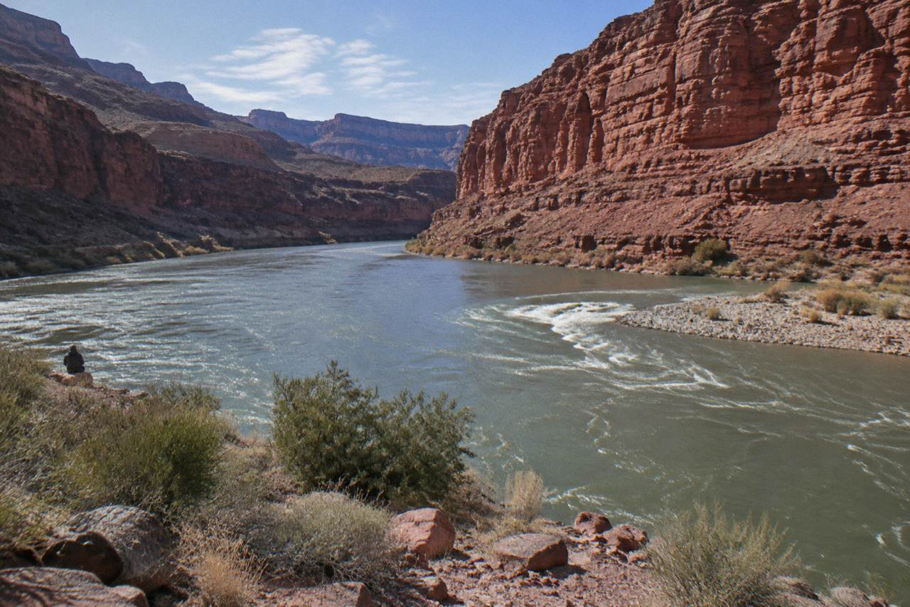 A wide river bend between tall red rock canyon walls under a clear sky