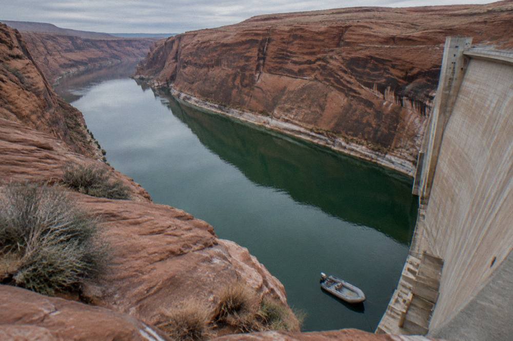 A motorized raft resting on calm river water below tall canyon cliffs