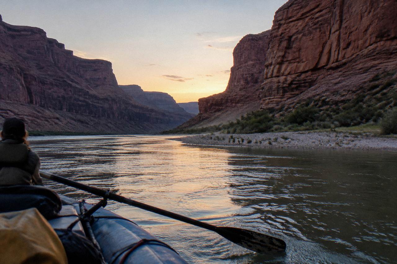 The Colorado River moving between steep dark rock walls inside a deep canyon