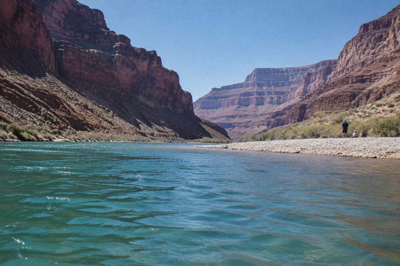 Calm turquoise water between tall canyon walls under a clear sky
