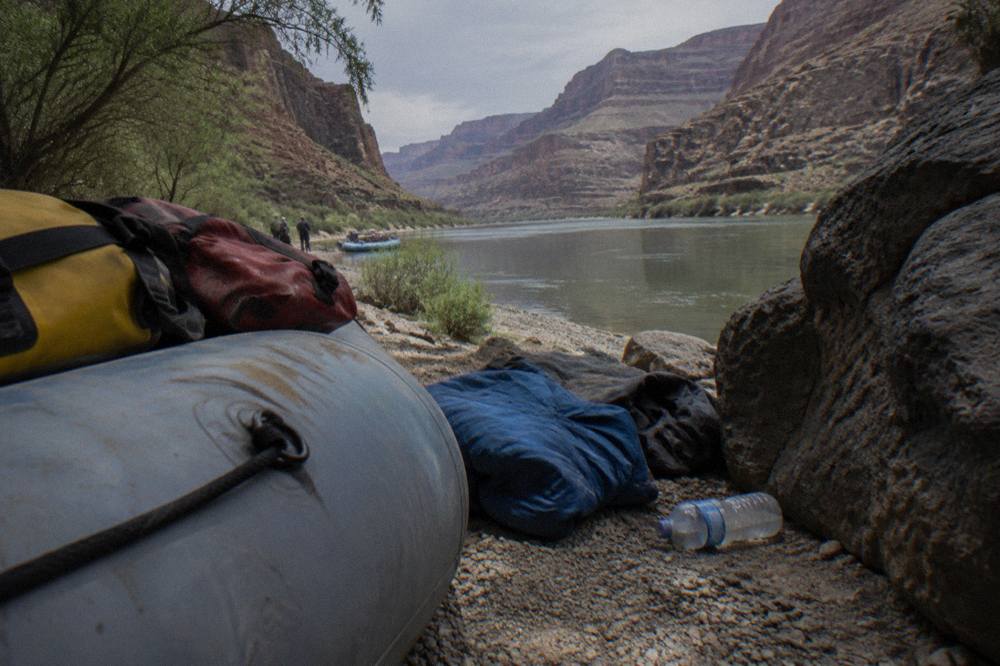 Dry bags and synthetic layers laid out on a raft tube beside the river