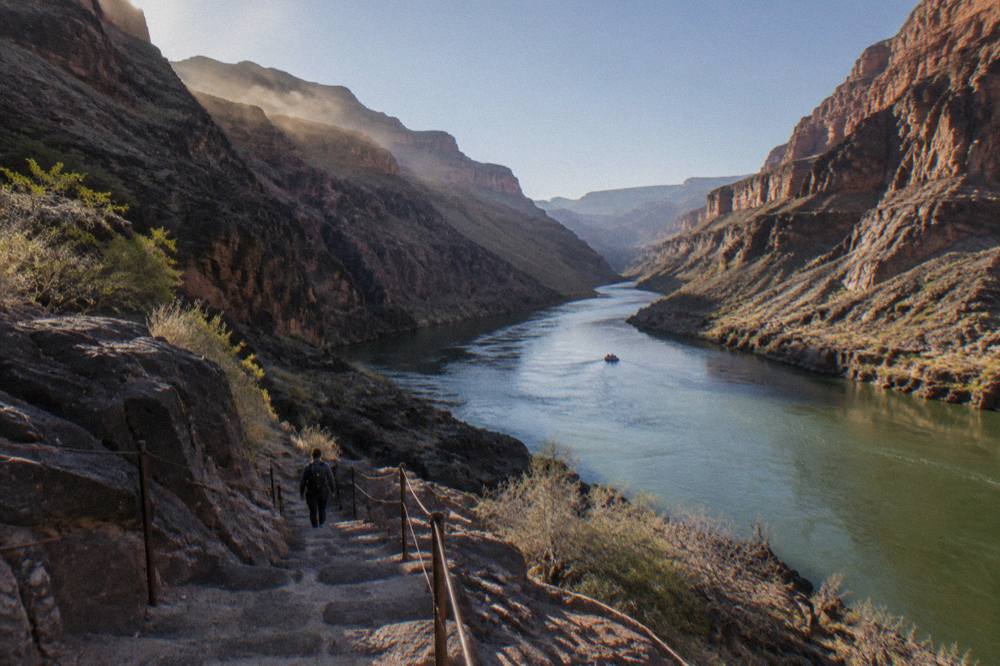 Smooth green river water between steep rock canyon walls under clear sky