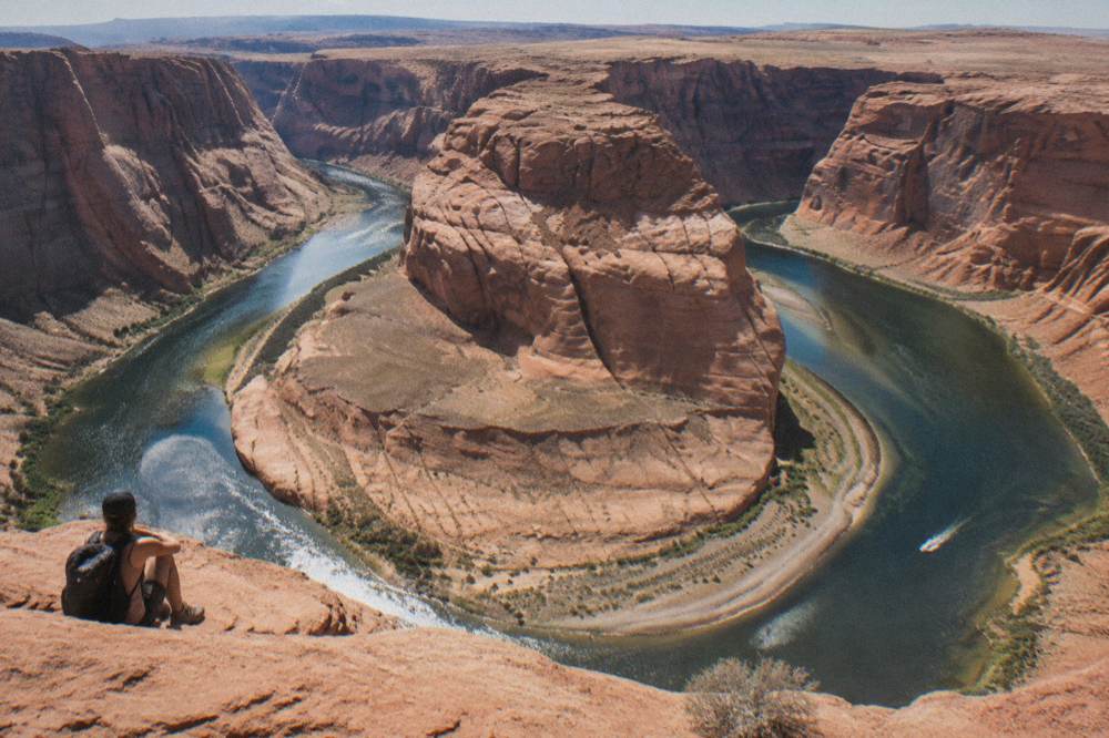 Wide desert river bend curving between layered orange rock walls at midday