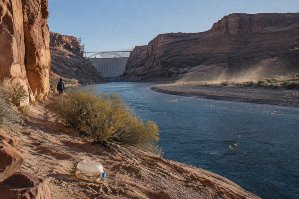 A wide desert river bending between layered sandstone cliffs under a clear sky