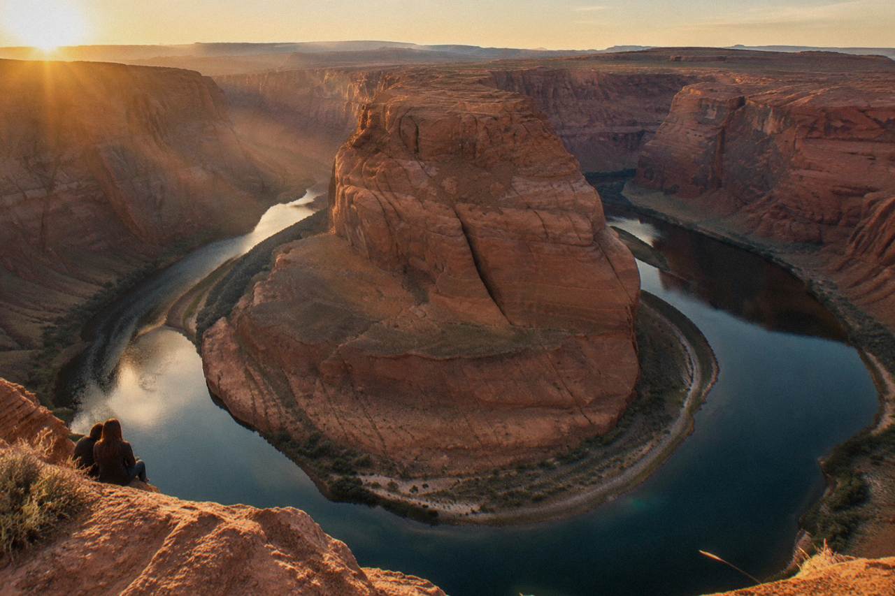 The Colorado River curving through the deep sandstone walls of Horseshoe Bend at golden hour.