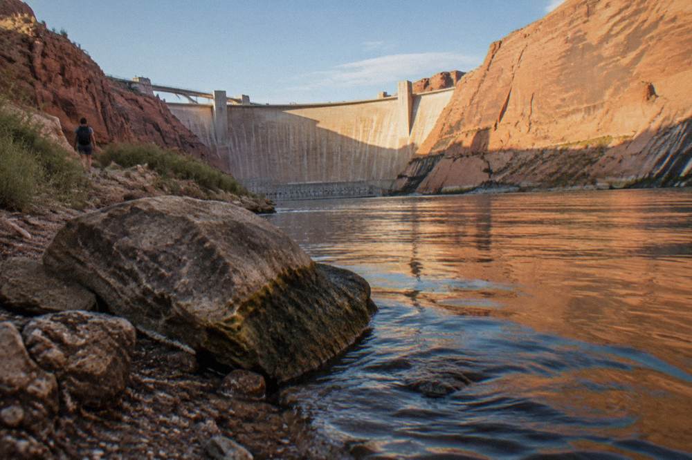 Low warm light on a wide river as it rounds a canyon wall in late afternoon.