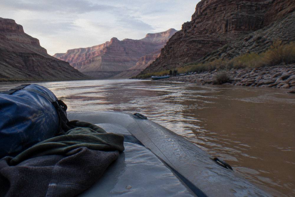 Dry bag and layered clothing set out on a raft seat beside a river