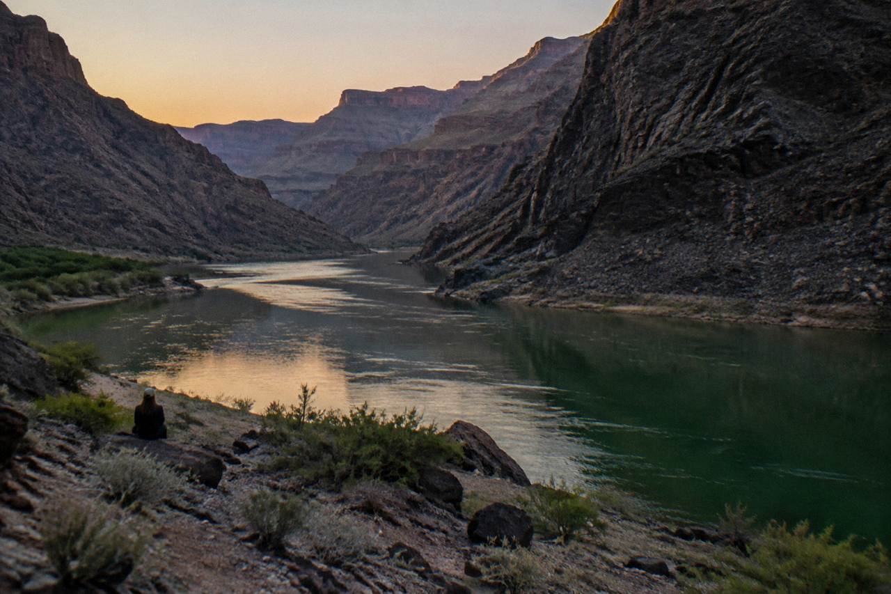 A calm green river channel between dark volcanic canyon walls reflecting on still water