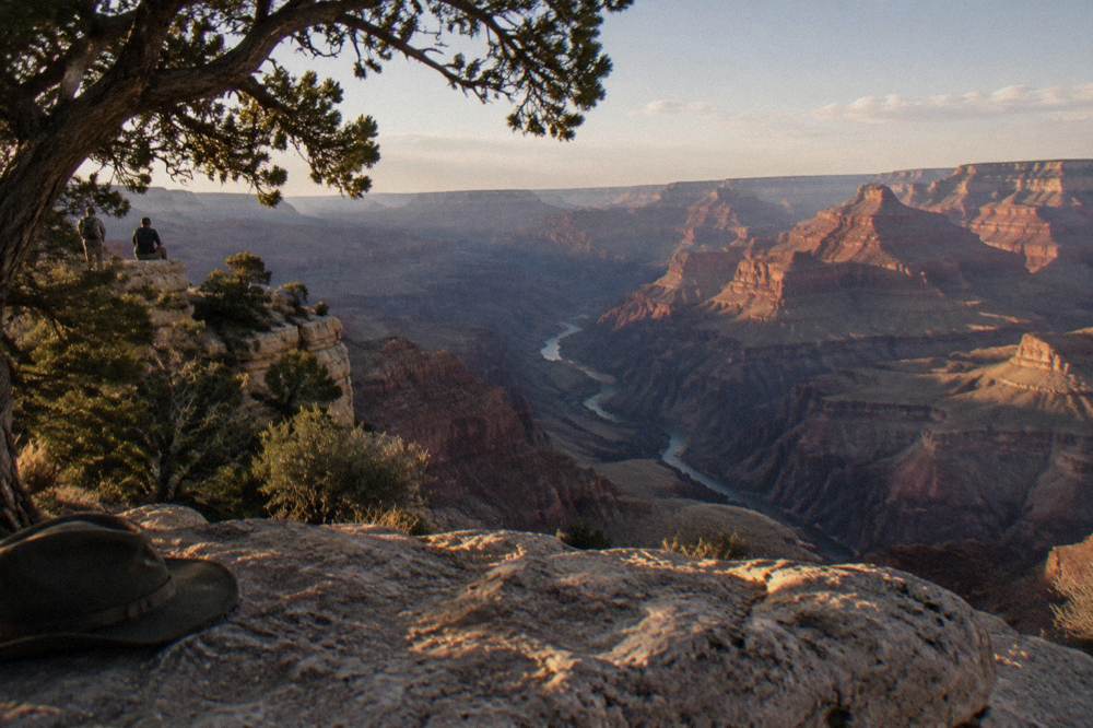 Stone rim edge overlooking layered canyon walls glowing in late afternoon light