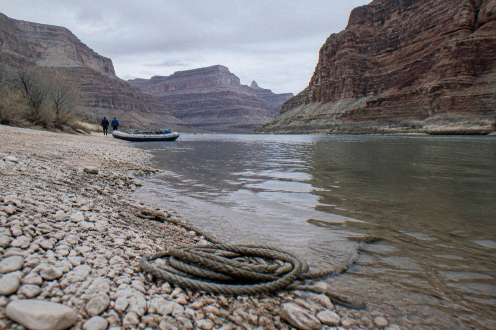 Quiet river shore with a gravel boat ramp and tall canyon walls in morning light