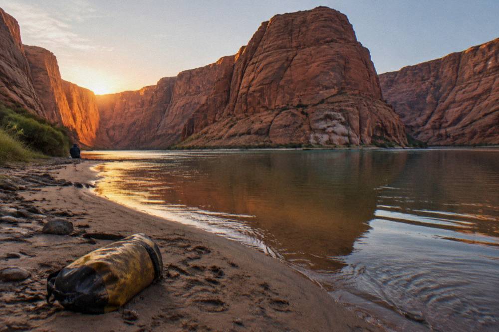 A sandbar beach on the inside of Horseshoe Bend with the river curving around tall red cliffs