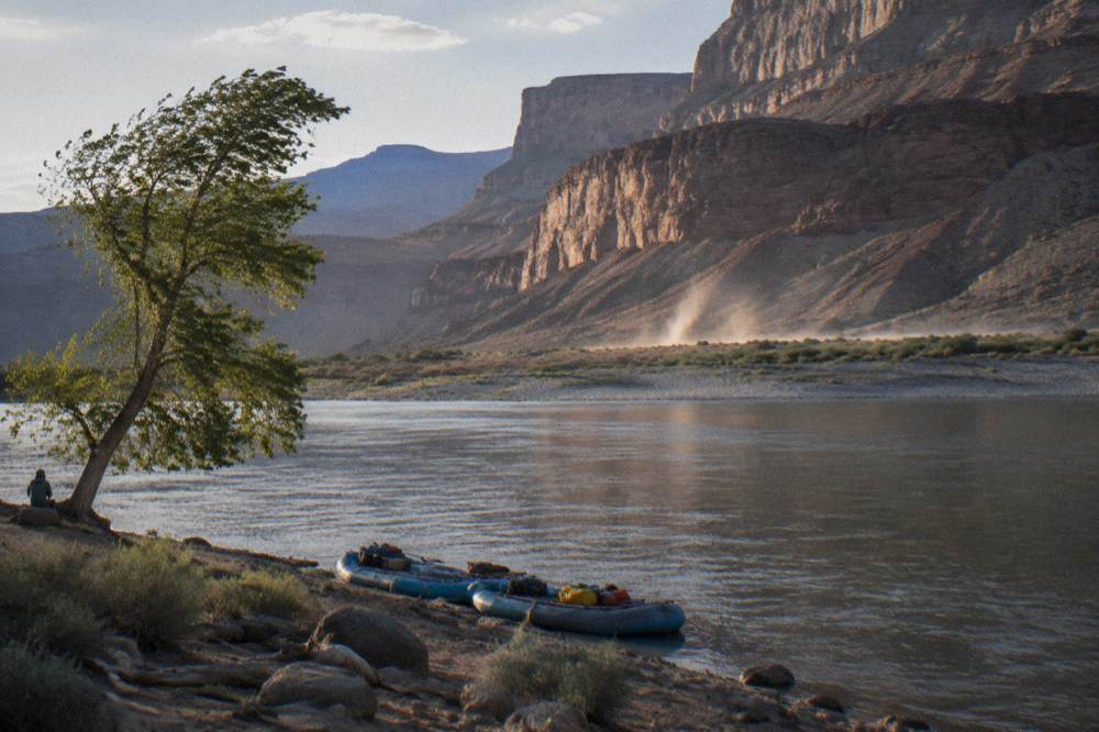 A wide view of the calm Colorado River between sandstone cliffs near Lees Ferry