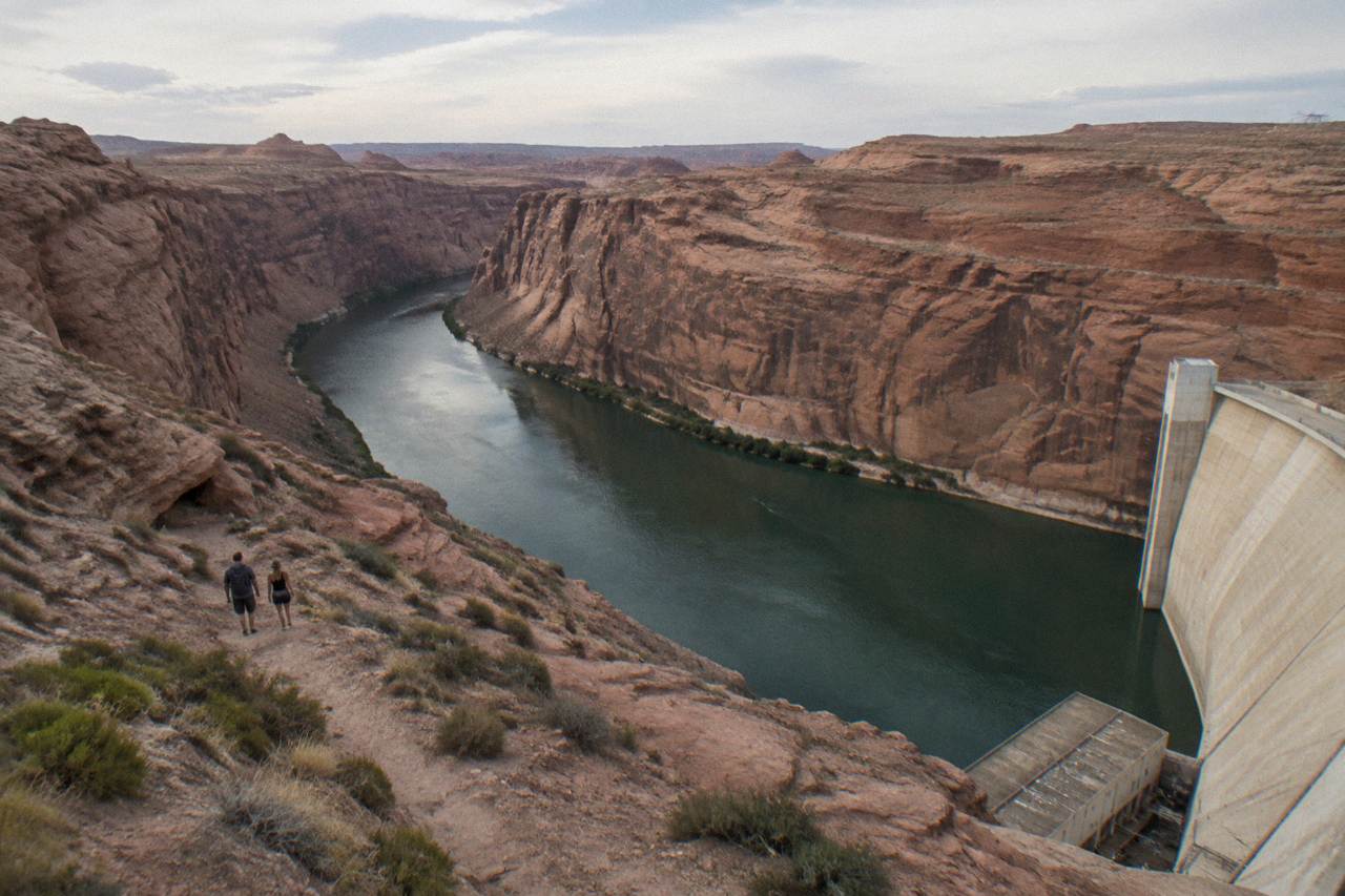 Smooth green water of the Colorado River winding through tall sandstone cliffs below Glen Canyon Dam