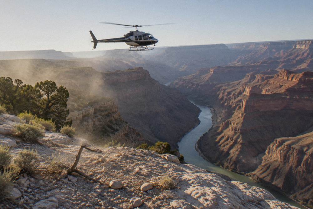 A helicopter hovering above a narrow canyon with the river winding below