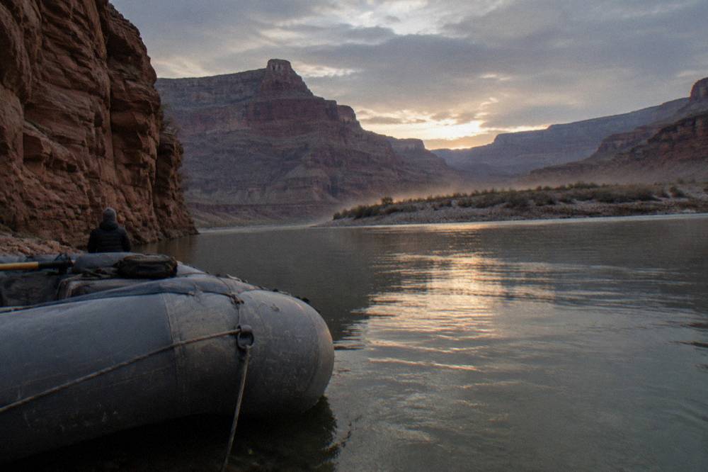 A raft floating between high canyon walls on calm green water