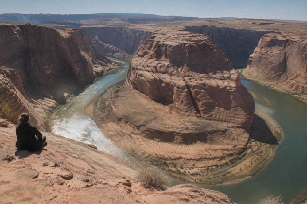 A wide view of the Colorado River curving through red rock canyon under a clear sky