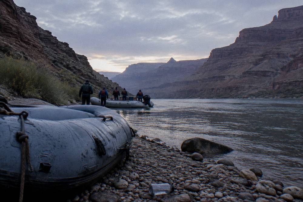 Passengers in life jackets boarding a motor raft at a stone river beach