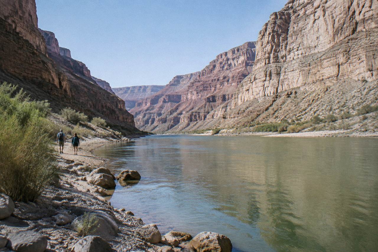 A calm stretch of the Colorado River winding between tall canyon walls under a clear sky