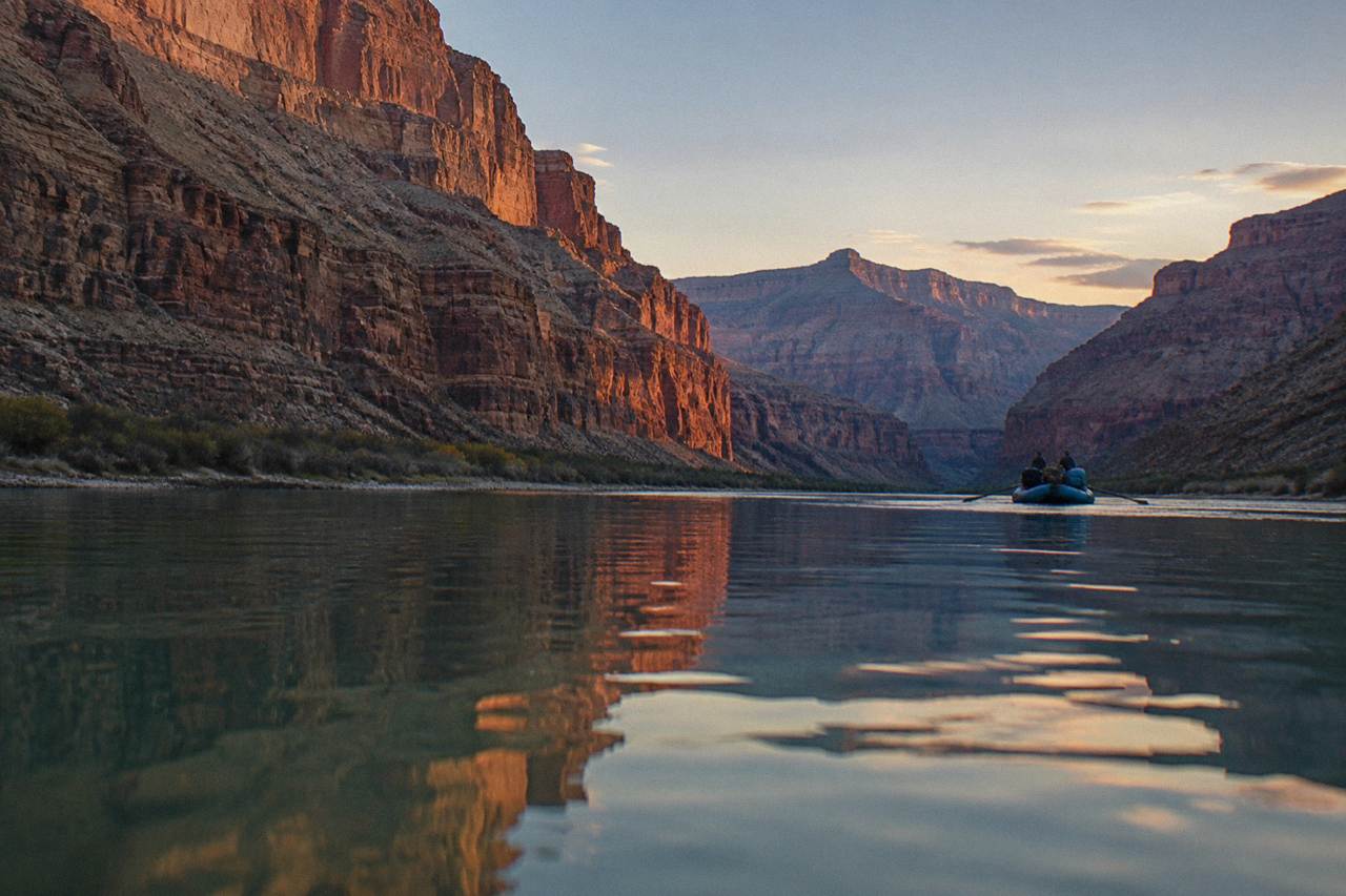 A calm stretch of the Colorado River reflecting canyon walls under an open sky
