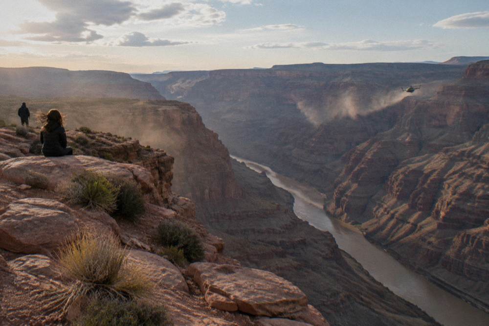 Helicopter flying along a wide canyon above the river