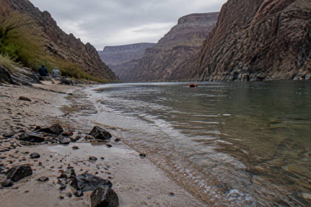 Shallow sandy beach at the edge of a river inside a narrow canyon