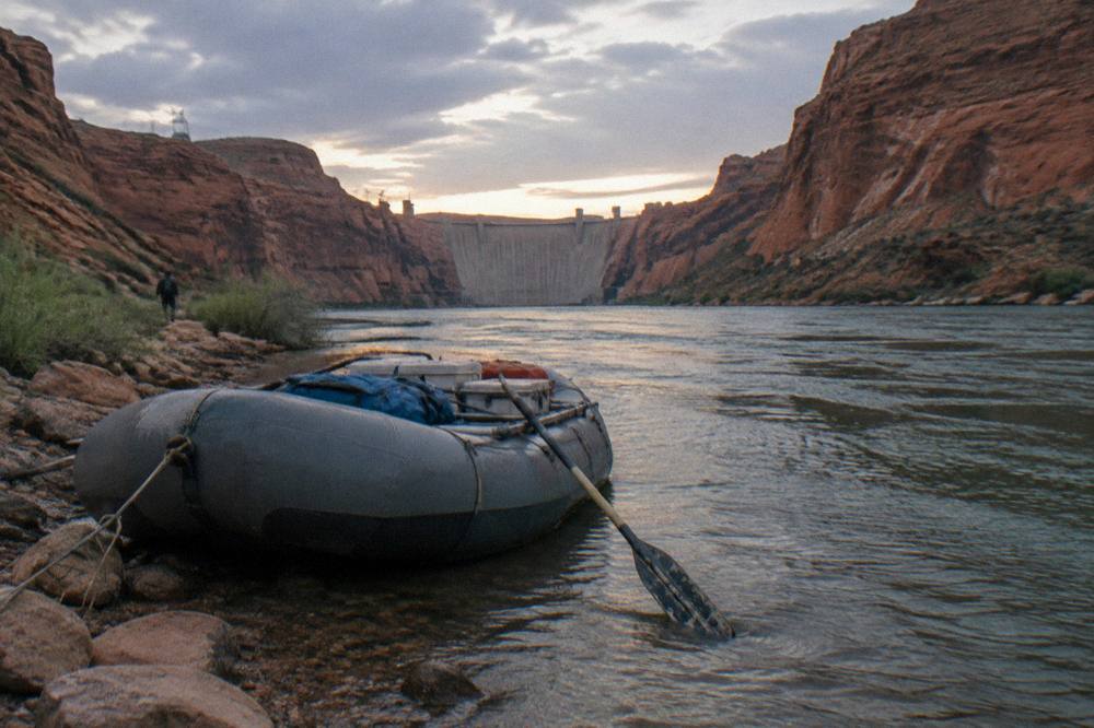 Tour raft moored at a rocky shoreline with canyon walls rising behind it