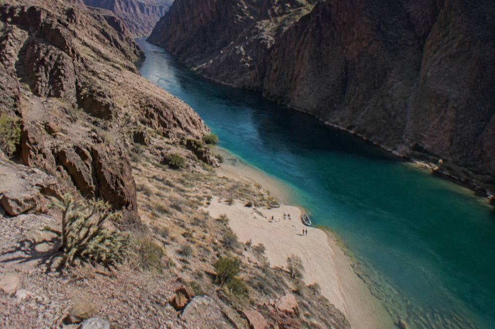 Calm turquoise water in a narrow canyon with dark rock walls rising on both sides