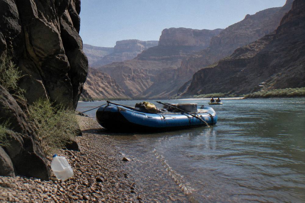 A raft moored at a small pebble beach beside steep rock walls