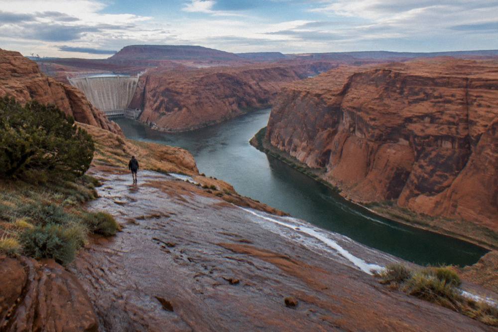 A wide view of the Colorado River winding between red rock walls under a clear sky