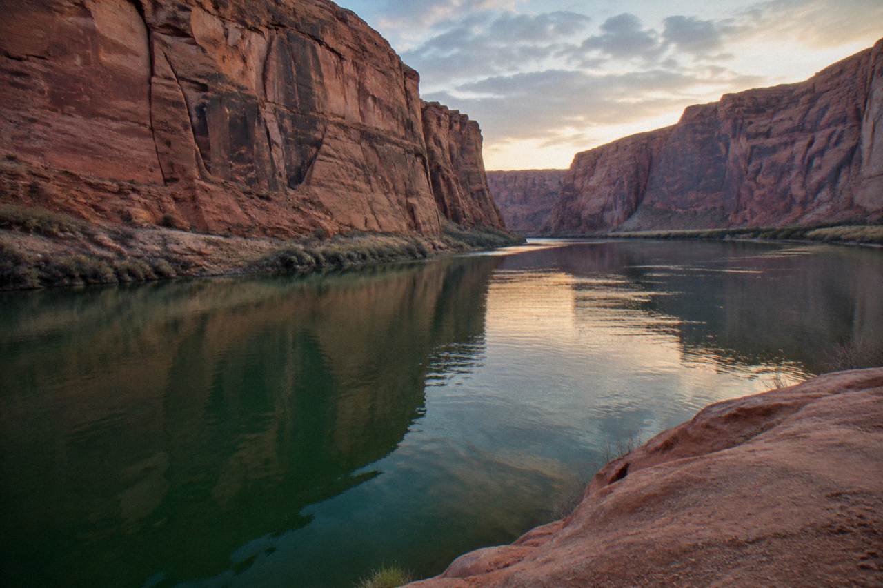 A calm stretch of the Colorado River reflecting red sandstone cliffs near Horseshoe Bend