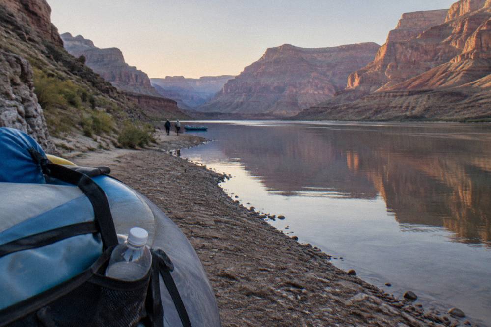 A calm stretch of the Colorado River reflecting canyon walls in early light