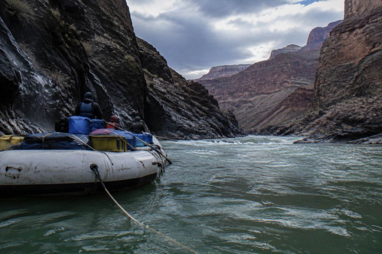 A motorized raft drifting between dark canyon walls on the Colorado River