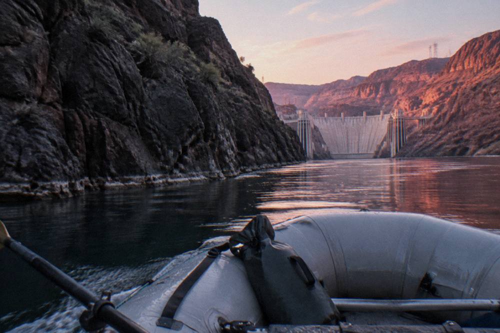 A motorized raft passing between dark volcanic rock walls on a calm river