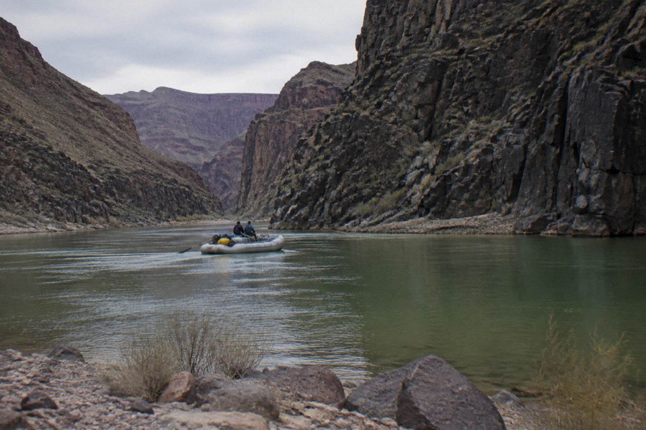 A raft floating on calm green water beneath tall canyon walls