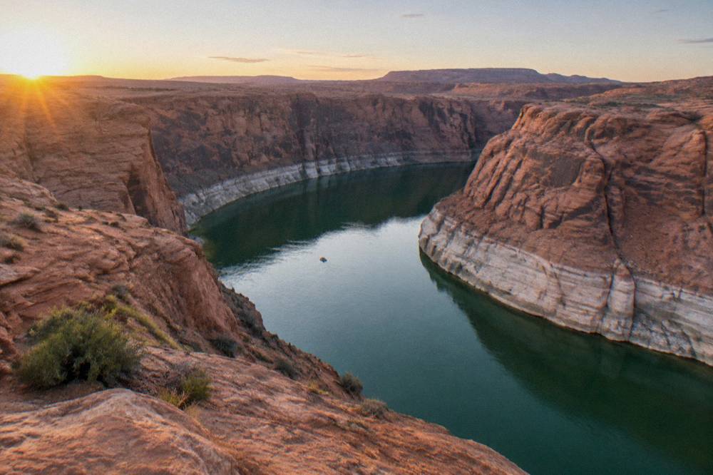 A wide bend of calm river curving between sheer sandstone cliffs